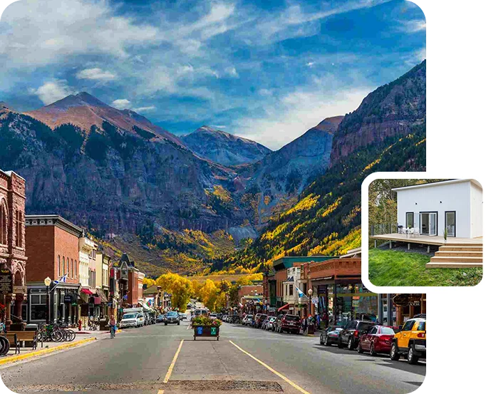 A street with cars parked on the side and mountains in the background.