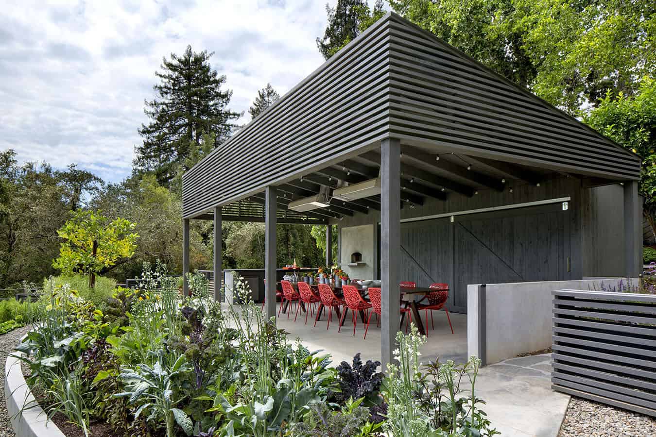 A covered patio with red chairs and plants.